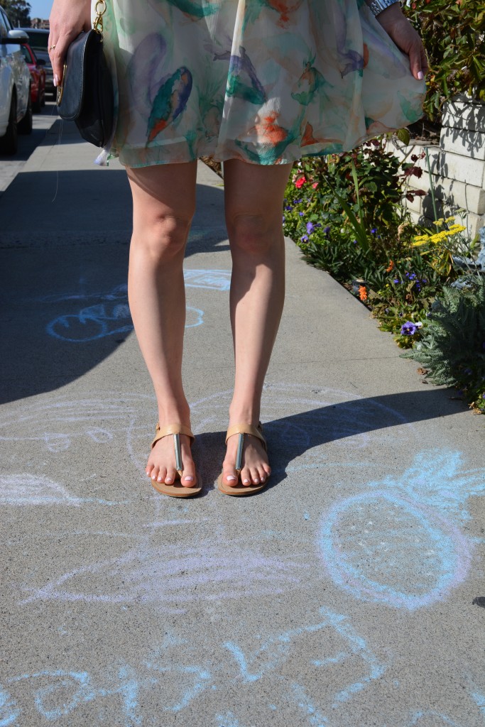 girl in gold flipflops standing over chalk