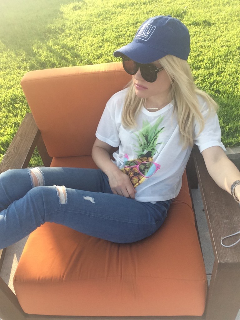 girl with her feet up in modern outdoor chair wearing baseball cap, pineapple shirt and ripped jeans Caitlin Hartley of Styled American http://styledamerican.com/nycs-newest-resident/