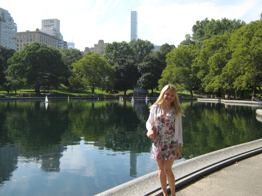 Caitlin Hartley of Styled American girl in floral dress in front of rowboats in Central Park