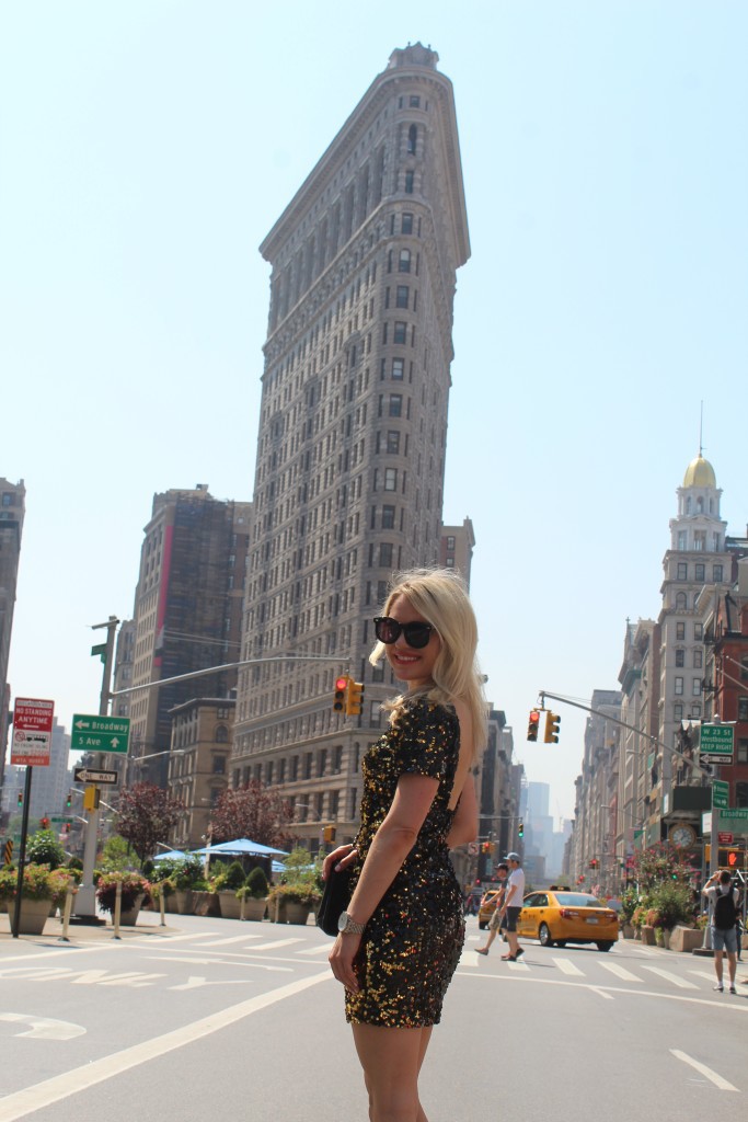 Caitlin Hartley of Styled American, girl i glam dress in front of flat iron building