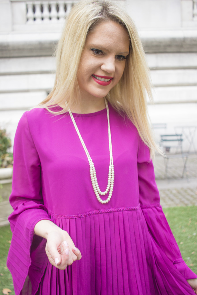 Caitlin Hartley of Styled American purple pleated dress with long sleeves