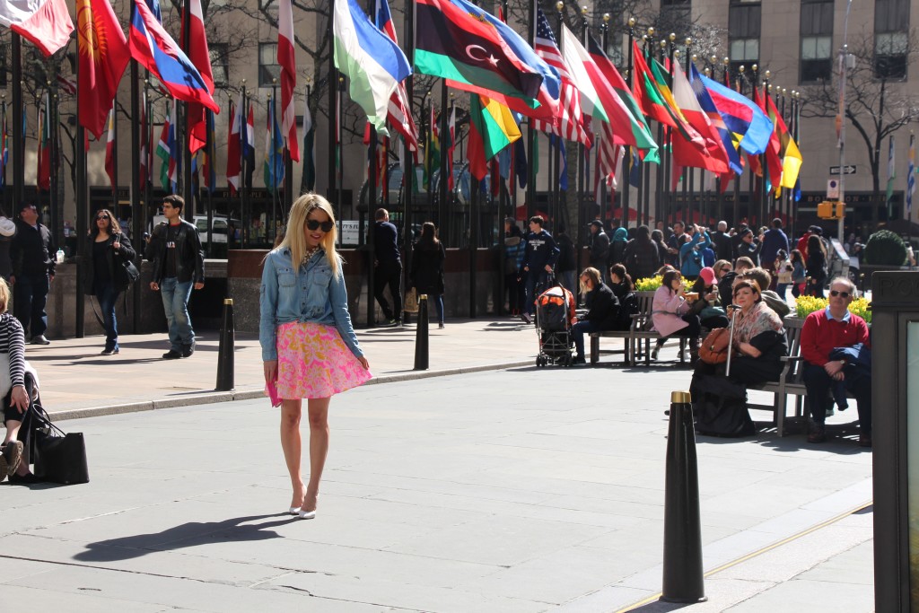 Caitlin Hartley of Styled American fashion blogger in front of flags at rockefeller plaza