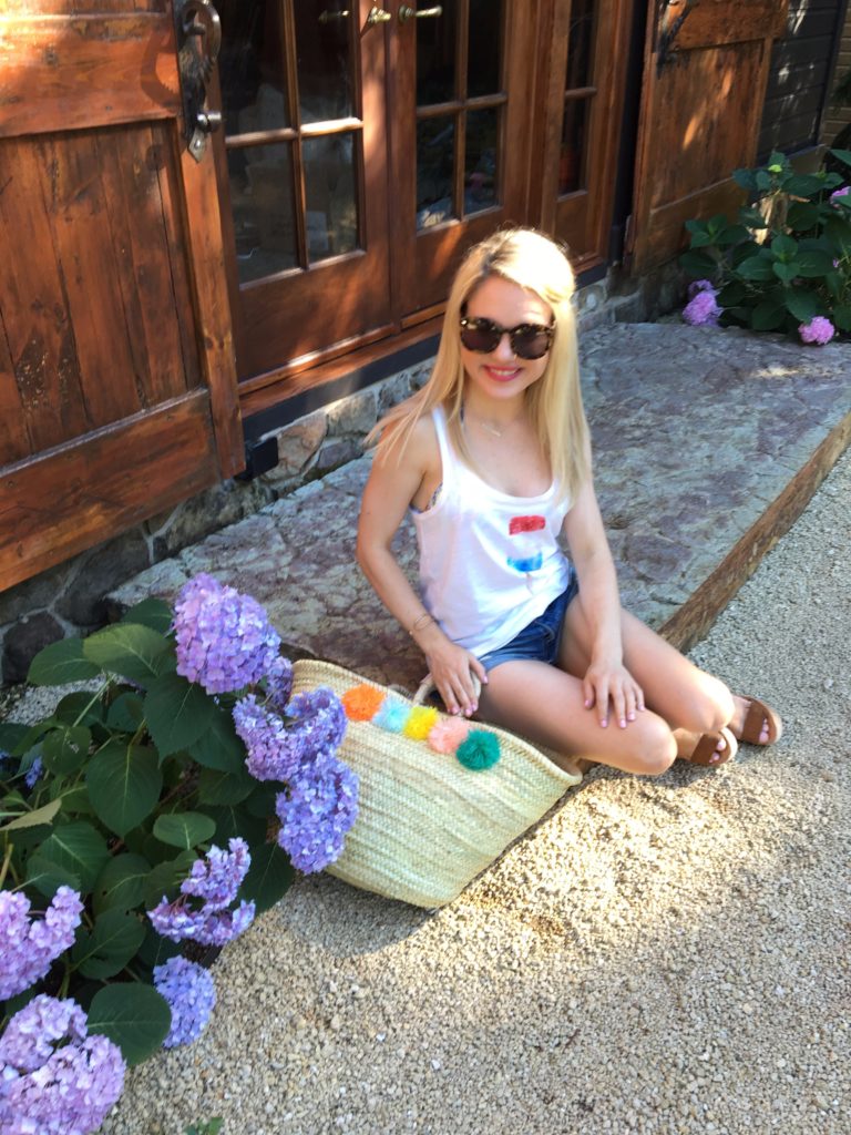 Caitlin-Hartley-of-Styled-American-in-popsicle-tank-top-distressed-jean-shorts-and-pop-pom beach-bag